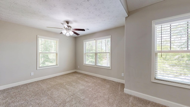 spare room featuring light colored carpet, baseboards, a ceiling fan, and a healthy amount of sunlight