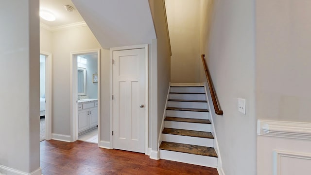stairway with crown molding, wood finished floors, and baseboards