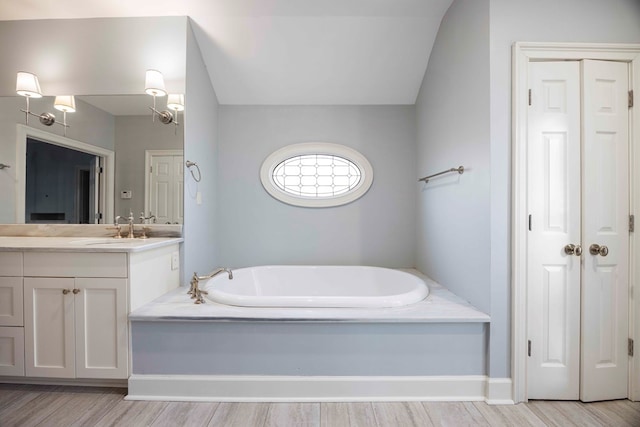 bathroom featuring vanity, wood-type flooring, and a tub to relax in