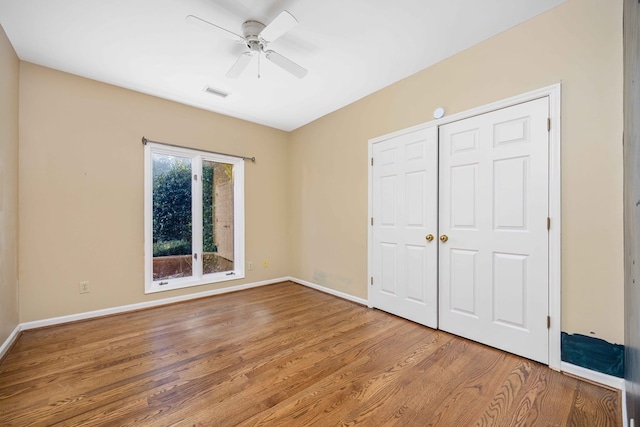 unfurnished bedroom with wood-type flooring, a closet, and ceiling fan