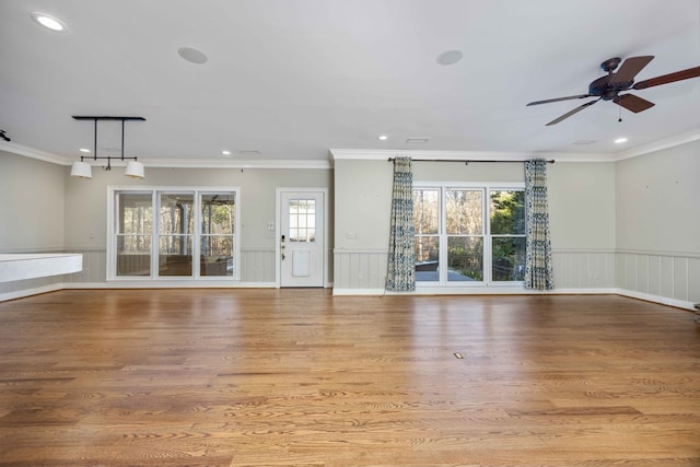 unfurnished living room featuring ceiling fan, ornamental molding, and light wood-type flooring