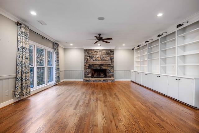 unfurnished living room featuring ornamental molding, ceiling fan, a fireplace, and light wood-type flooring