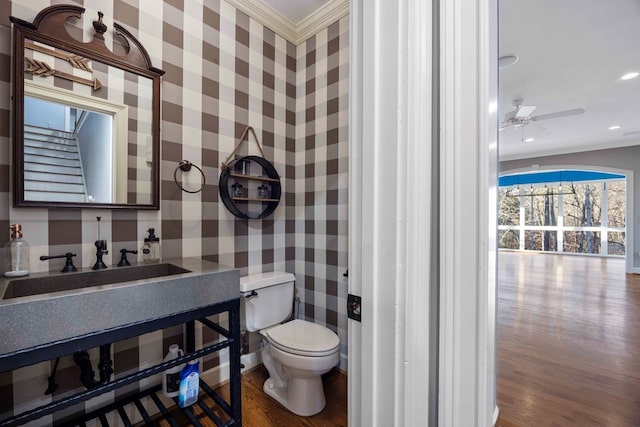 bathroom featuring wood-type flooring, crown molding, ceiling fan, and toilet