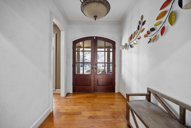 foyer entrance featuring crown molding, light wood-type flooring, and french doors