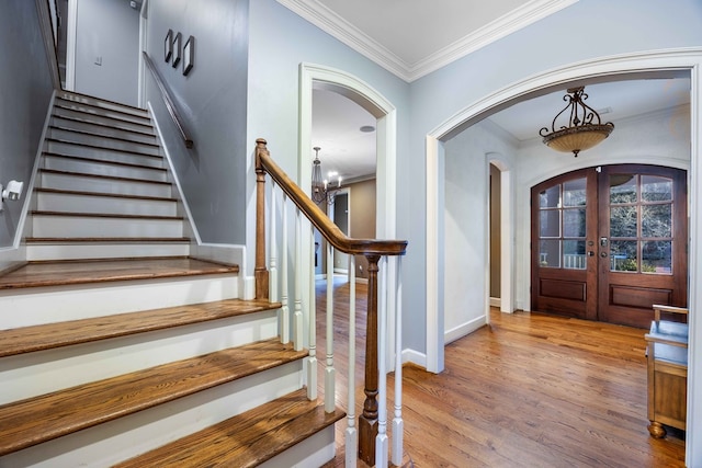 entrance foyer featuring crown molding, an inviting chandelier, light wood-type flooring, and french doors