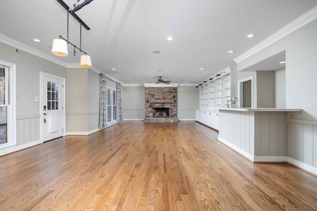 unfurnished living room with crown molding, ceiling fan, a fireplace, and light hardwood / wood-style flooring