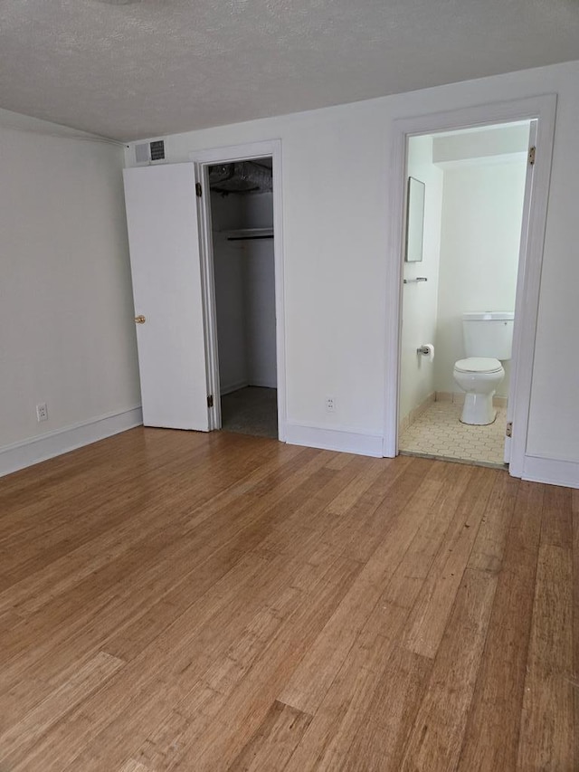 2323 Devonshire Dr, Columbus, GA 31904 - unfurnished bedroom featuring wood finished floors, baseboards, a spacious closet, ensuite bath, and a textured ceiling
