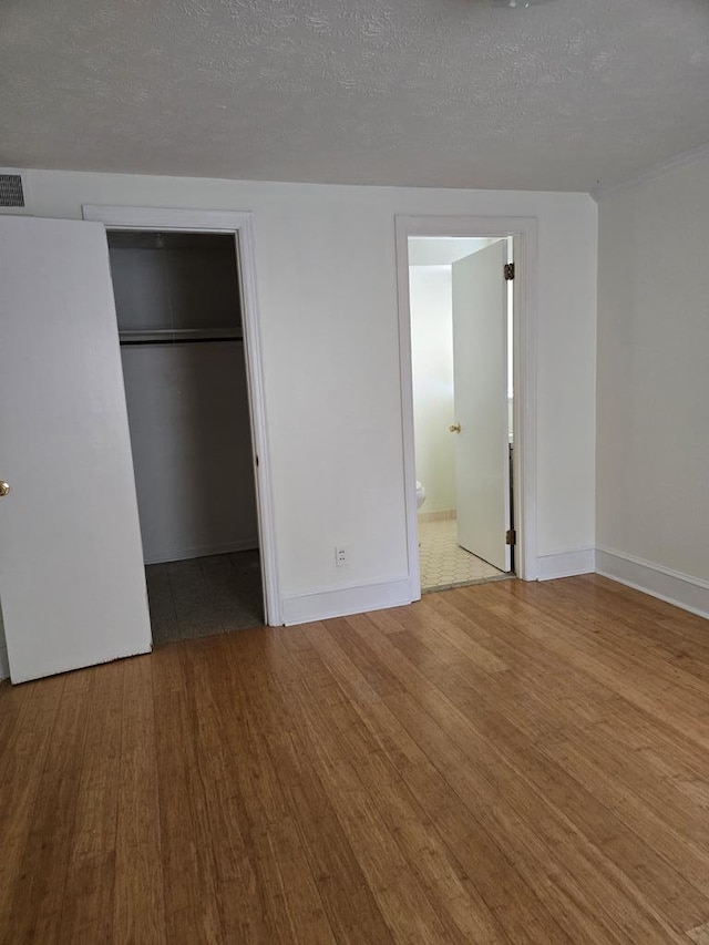 2323 Devonshire Dr, Columbus, GA 31904 - unfurnished bedroom with wood finished floors, a spacious closet, baseboards, ensuite bath, and a textured ceiling
