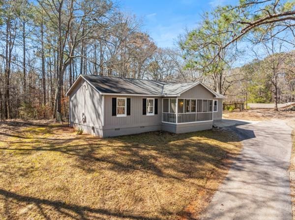 view of home's exterior featuring a lawn, driveway, crawl space, and a sunroom