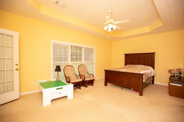 bedroom with ceiling fan, a raised ceiling, and light carpet