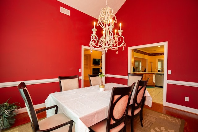 dining area featuring hardwood / wood-style floors, high vaulted ceiling, and an inviting chandelier