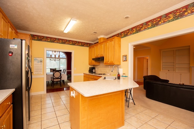 kitchen with stainless steel fridge, light tile patterned floors, ornamental molding, kitchen peninsula, and a breakfast bar area