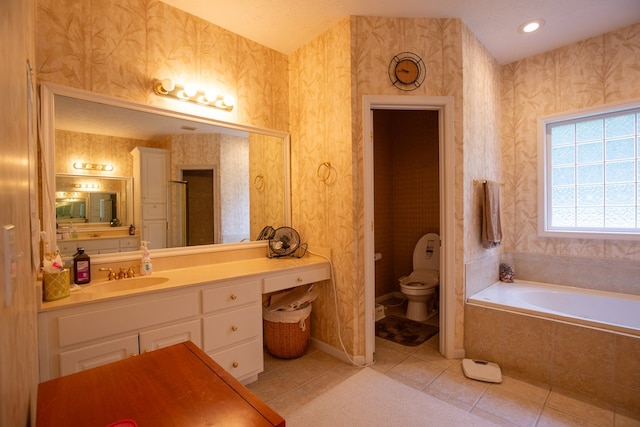 bathroom featuring tile patterned flooring, a relaxing tiled tub, toilet, and vanity