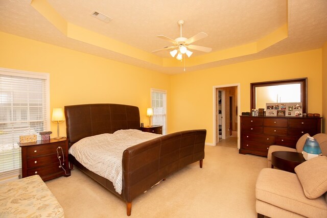 carpeted bedroom with a tray ceiling, ceiling fan, and a textured ceiling