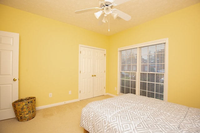 carpeted bedroom with ceiling fan, a textured ceiling, and a closet