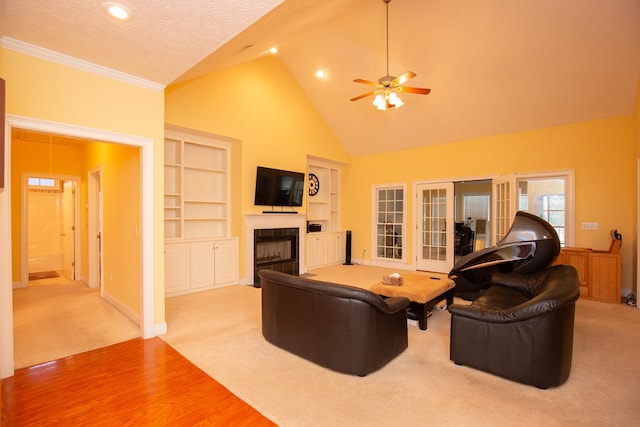 living room featuring built in shelves, ceiling fan, light hardwood / wood-style flooring, high vaulted ceiling, and a textured ceiling