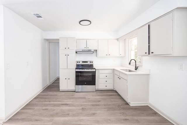 2104 Wellborn Dr, Columbus, GA 31907 - kitchen with stainless steel electric stove, under cabinet range hood, white cabinets, light countertops, and light wood-style flooring
