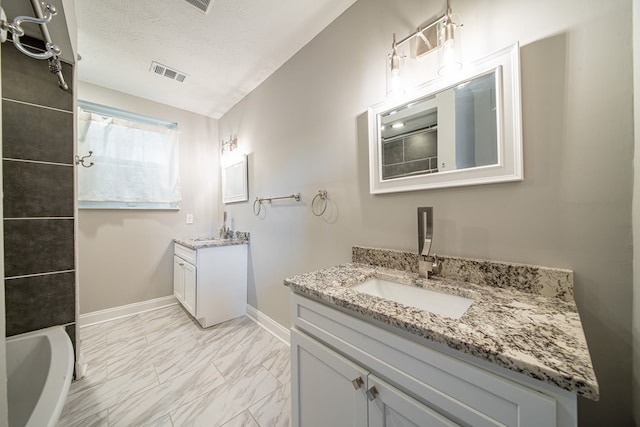 2027 Preston Dr, Columbus, GA 31906 - bathroom featuring marble finish flooring, two vanities, baseboards, a textured ceiling, and a bath