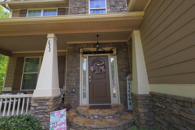 entrance to property featuring covered porch and stone siding