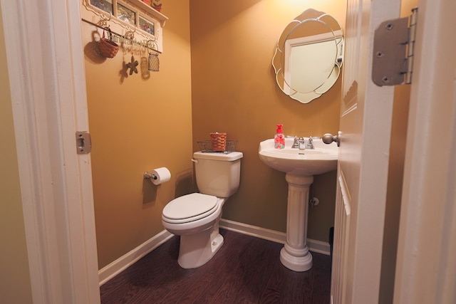 bathroom with toilet, baseboards, a sink, and wood finished floors