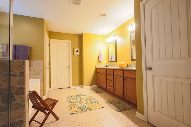bathroom featuring visible vents, double vanity, baseboards, tiled shower, and tile patterned floors