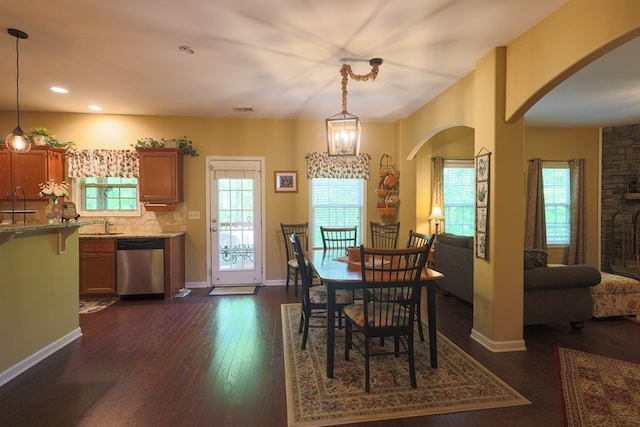 dining room featuring arched walkways, dark wood-style floors, and a wealth of natural light