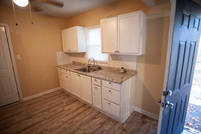 kitchen with sink, dark hardwood / wood-style floors, white cabinets, light stone countertops, and backsplash