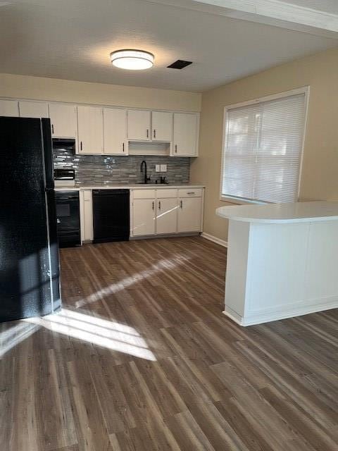 kitchen featuring dark hardwood / wood-style flooring, tasteful backsplash, sink, black appliances, and white cabinetry