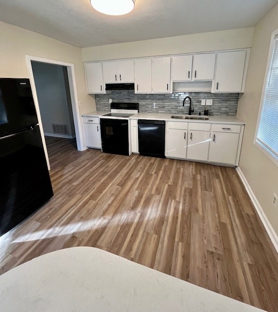 kitchen featuring black appliances, white cabinets, sink, tasteful backsplash, and light hardwood / wood-style floors