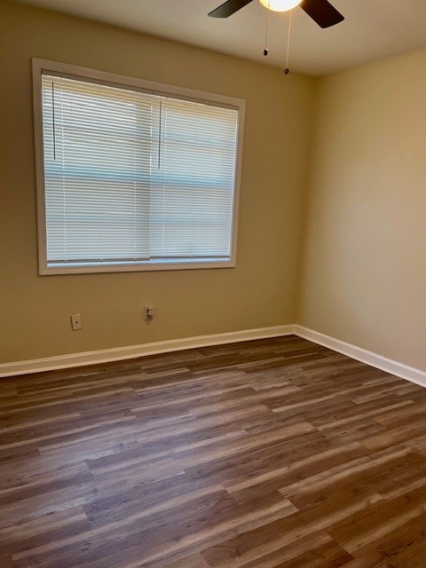 unfurnished room with ceiling fan and dark wood-type flooring