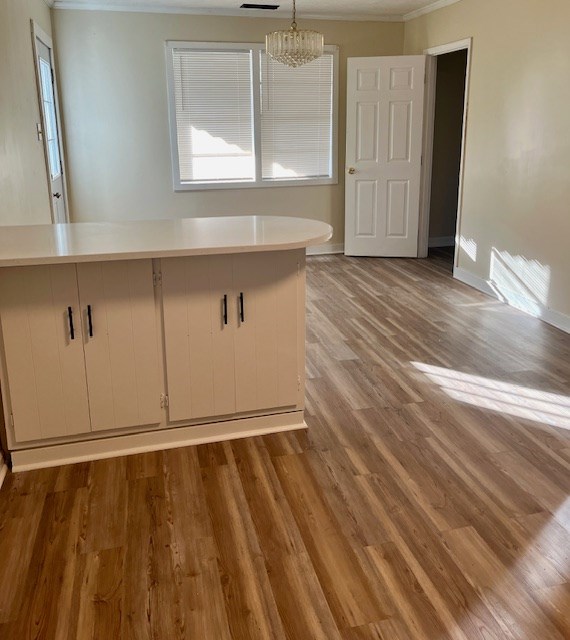 interior space with hardwood / wood-style flooring, ornamental molding, and an inviting chandelier