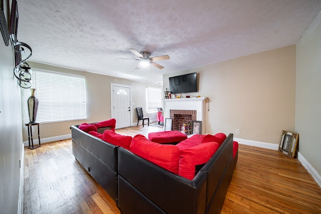 1605 39th St, Columbus, GA 31904 - living room with a ceiling fan, wood finished floors, a textured ceiling, and a brick fireplace