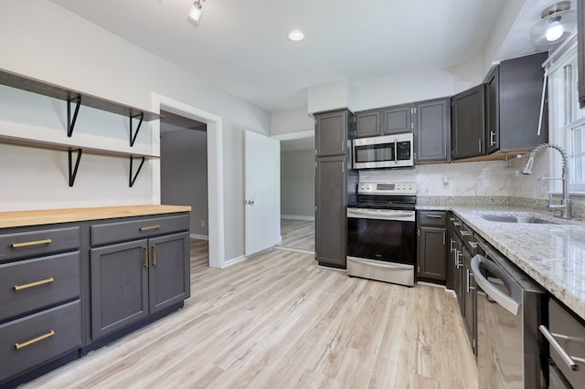 3775 Steam Mill Rd, Columbus, GA 31906 - kitchen with appliances with stainless steel finishes, open shelves, light wood finished floors, backsplash, and light stone counters