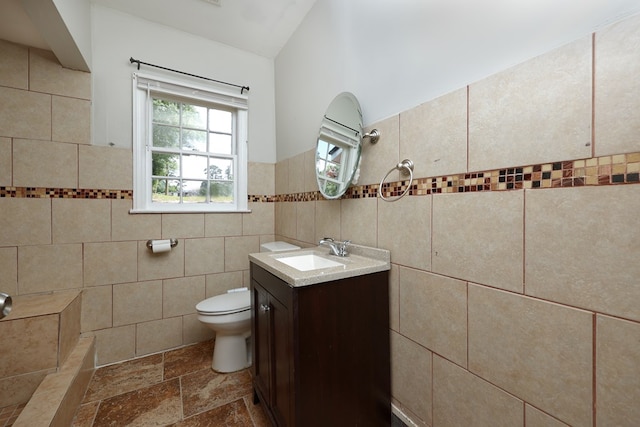 3775 Steam Mill Rd, Columbus, GA 31906 - bathroom featuring tile walls, vanity, stone tile flooring, and vaulted ceiling