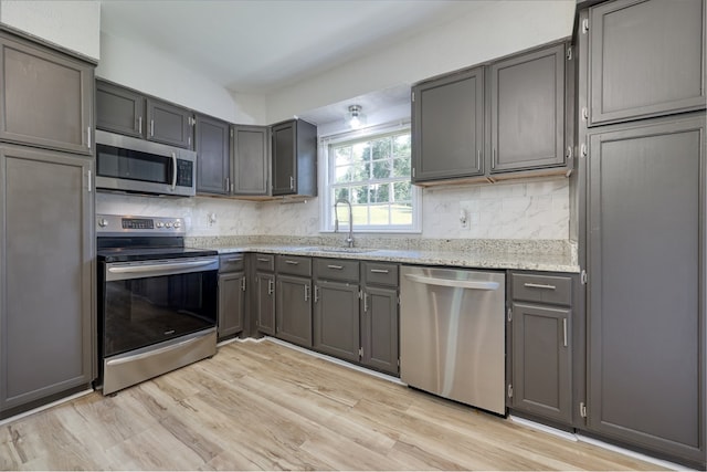 3775 Steam Mill Rd, Columbus, GA 31906 - kitchen featuring appliances with stainless steel finishes, tasteful backsplash, light wood-style floors, light stone counters, and gray cabinetry