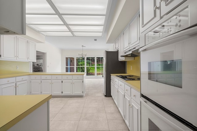 1425 Dartmouth Rd, Columbus, GA 31904 - kitchen featuring under cabinet range hood, a peninsula, light countertops, white cabinetry, and light tile patterned floors