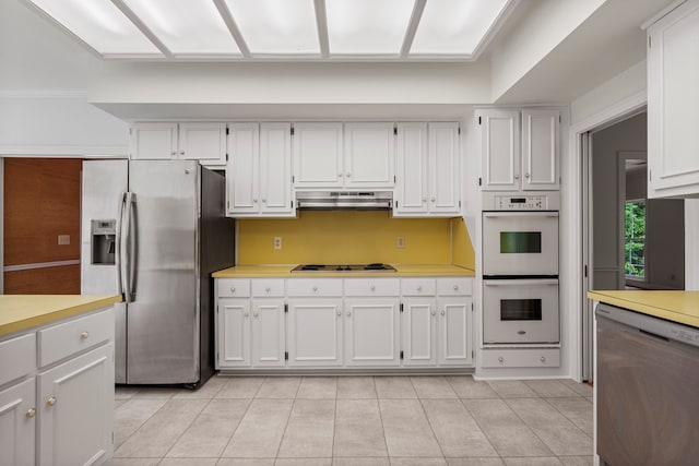 1425 Dartmouth Rd, Columbus, GA 31904 - kitchen with appliances with stainless steel finishes, light countertops, under cabinet range hood, light tile patterned floors, and white cabinetry