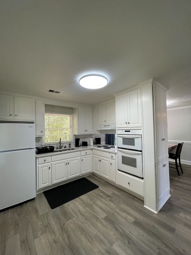 1023 Maridele Dr, Columbus, GA 31904 - kitchen with white appliances, a sink, wood finished floors, white cabinets, and under cabinet range hood