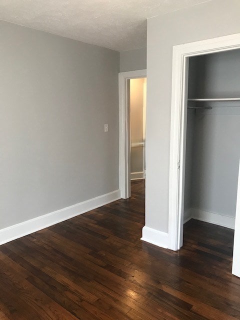 unfurnished bedroom featuring dark wood-type flooring and a closet