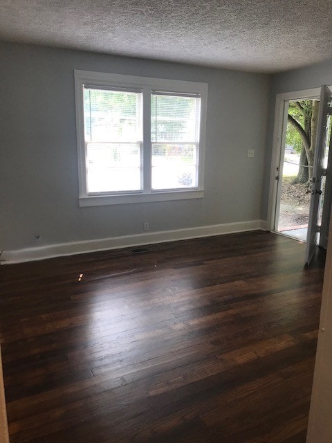 spare room with a textured ceiling and dark wood-type flooring