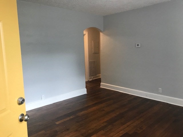 spare room with a textured ceiling and dark hardwood / wood-style floors