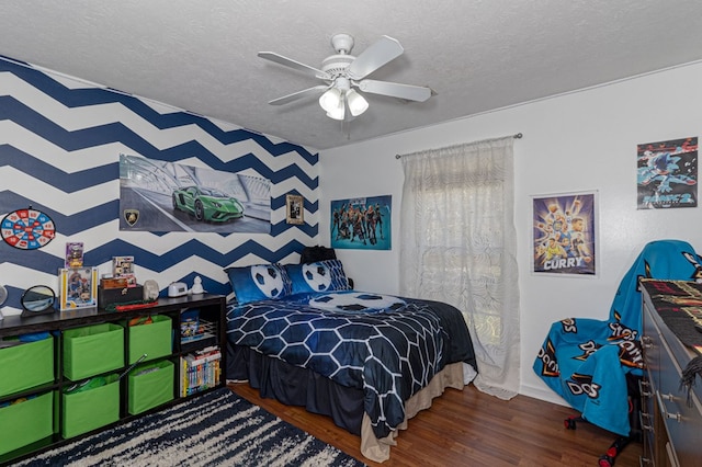 bedroom with wood finished floors, a textured ceiling, a ceiling fan, and baseboards