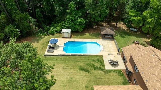 pool with a yard, a storage shed, a patio, and an outbuilding