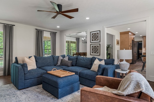 living room with light wood-type flooring, ceiling fan with notable chandelier, and recessed lighting