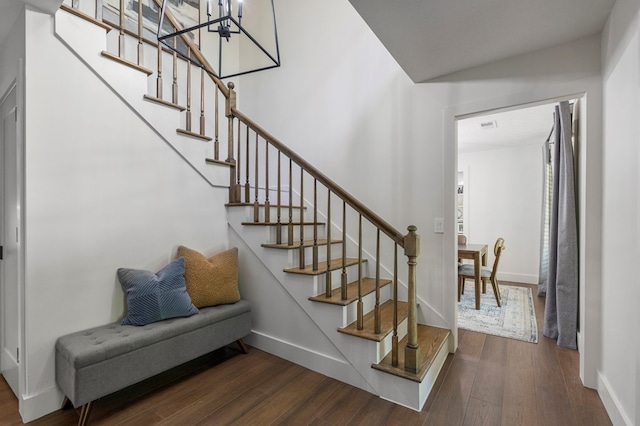 staircase featuring baseboards, a notable chandelier, and wood finished floors