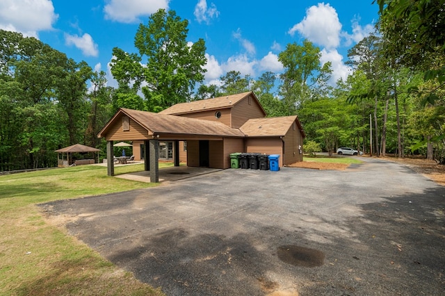 view of front facade featuring roof with shingles, a front yard, and aphalt driveway