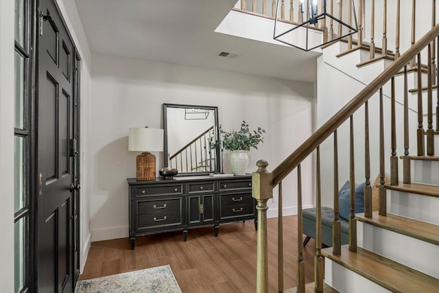 entrance foyer featuring baseboards, stairway, visible vents, and wood finished floors