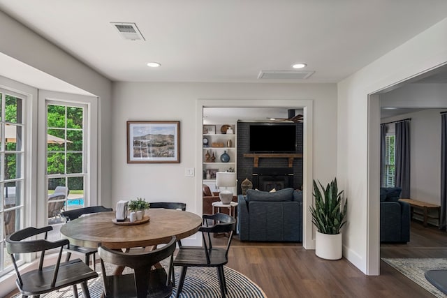 dining space featuring baseboards, a fireplace, visible vents, and dark wood-style floors
