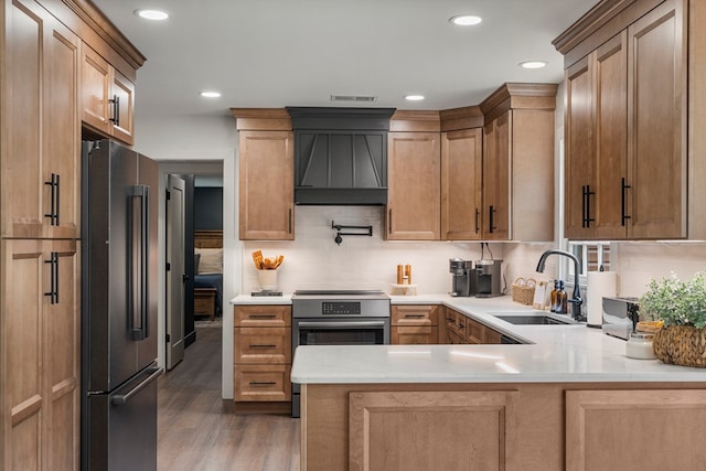 kitchen with a sink, a peninsula, premium range hood, wood finished floors, and high end black fridge