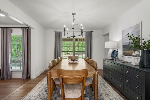 dining area with a chandelier, light wood-style flooring, baseboards, and a healthy amount of sunlight